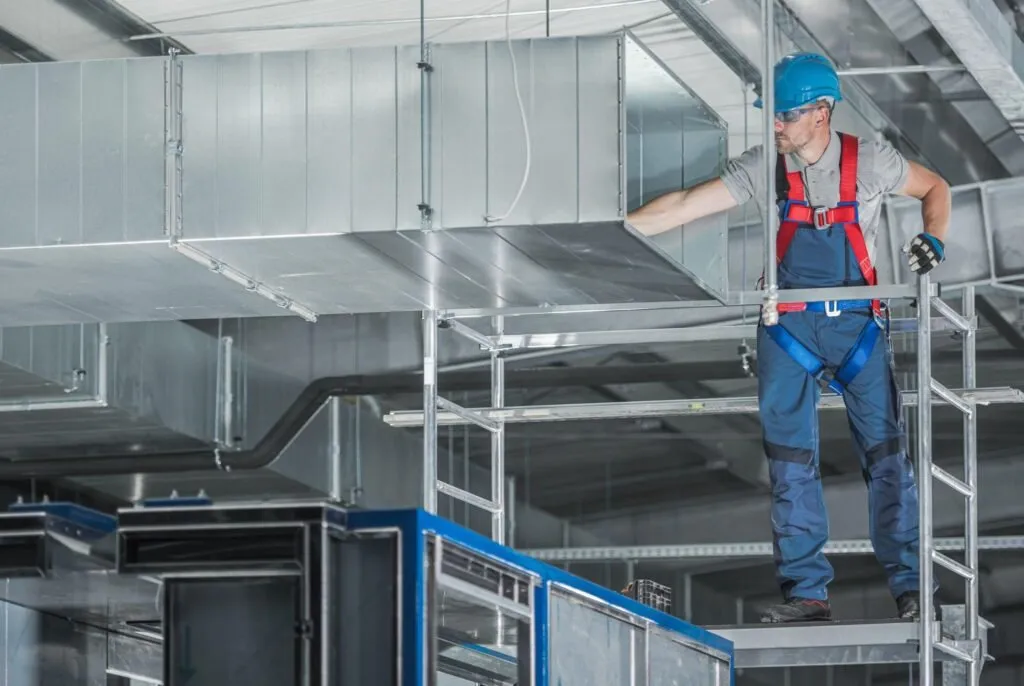 Engineers installing a commercial HVAC duct system.